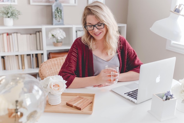 Thuis-zittende vrouw die werkt achter haar laptop